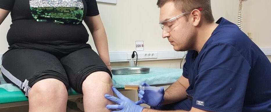 Lekarz ortopeda wykonuje zastrzyk śródstawowy do stawu kolanowego z powodu choroby zwyrodnieniowej stawów